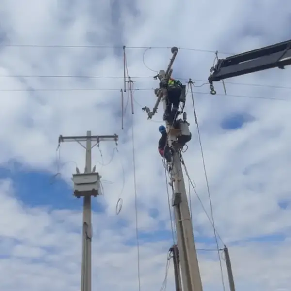 Camión pluma izando un poste durante la construcción de una red eléctrica