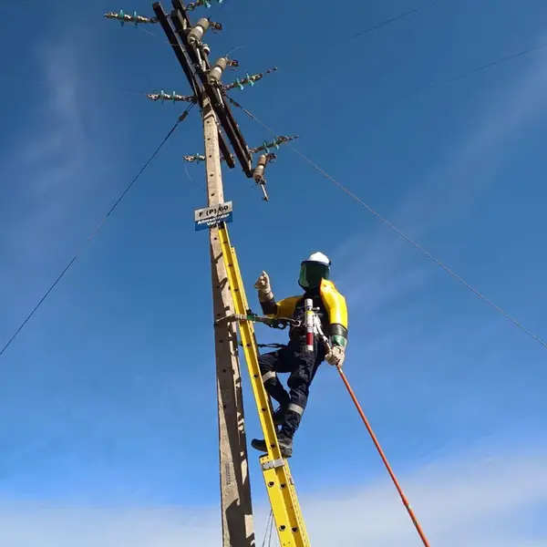 Operario de GES Ingeniería sobre escalera conectando una línea en un poste