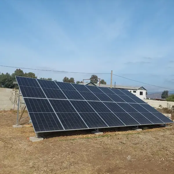 Paneles solares sobre estructura metálica montada en el suelo junto a una vivienda